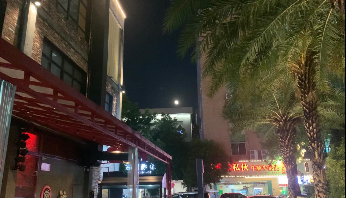 The moon is at the top of the building across.